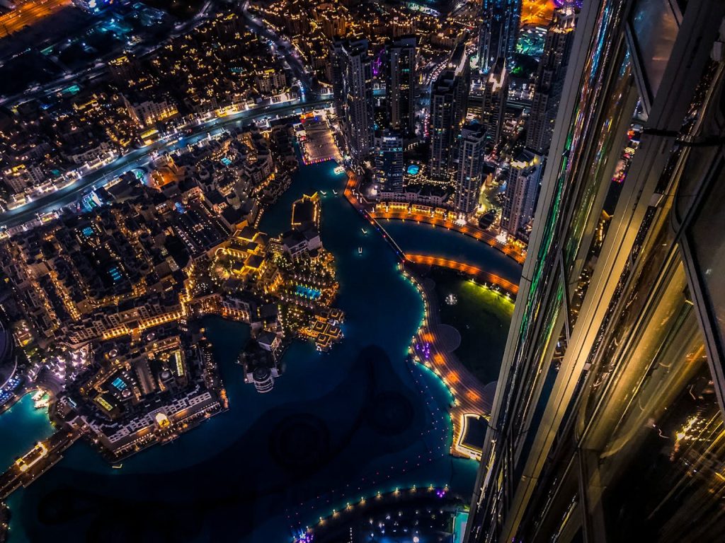 Vibrant aerial cityscape of Dubai at night with illuminated skyscrapers and urban landscape.